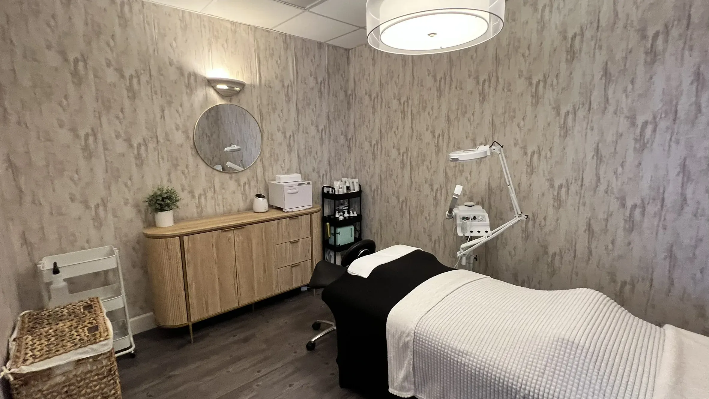 Elevé Esthetics treatment room with a round mirror and facial equipment